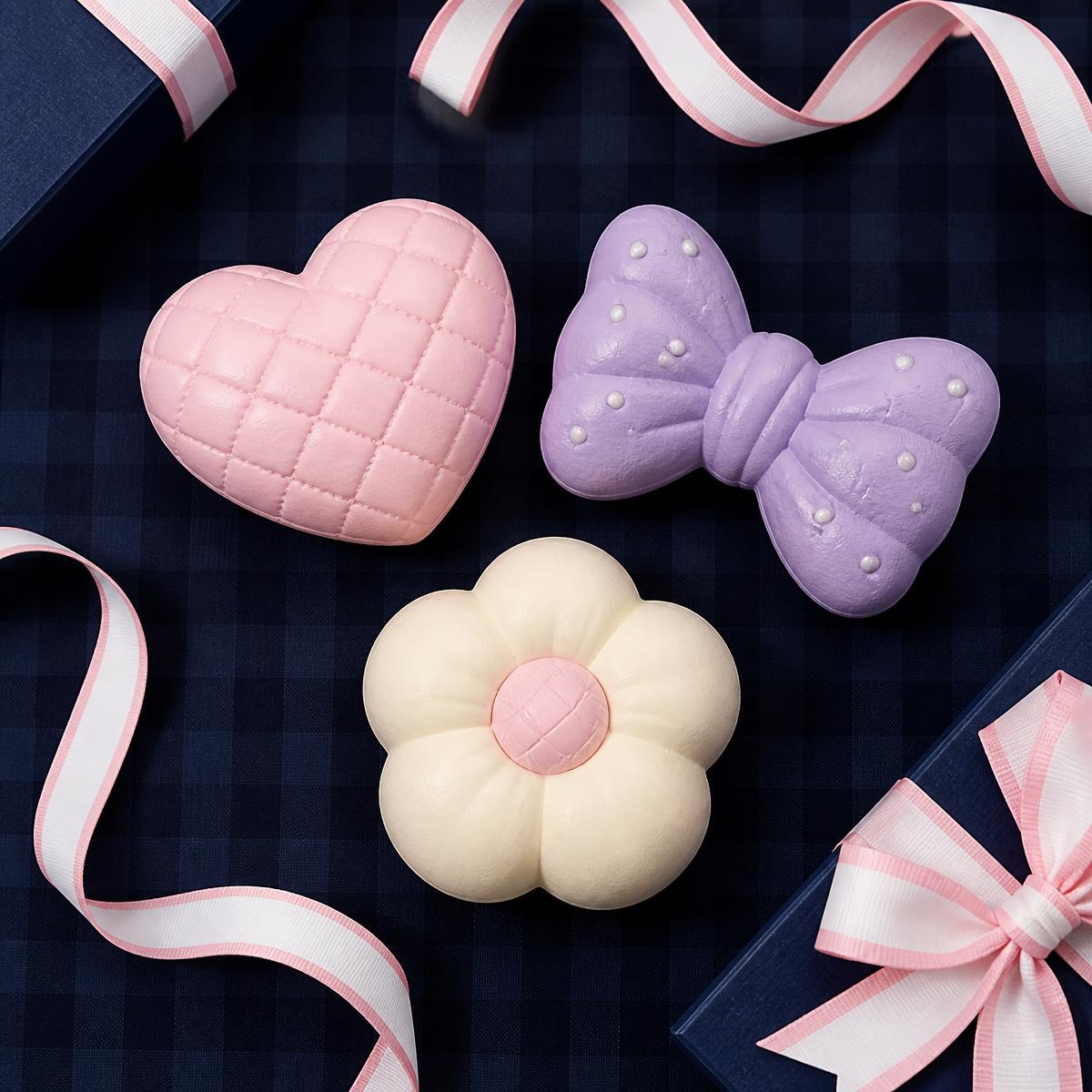 Premium hand-poured squishies in pink, lavender, and cream on a navy gingham backdrop